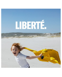 A child running on a beach while holding a yellow jacket