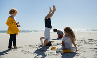 A group of kids on a beach playing and having fun

